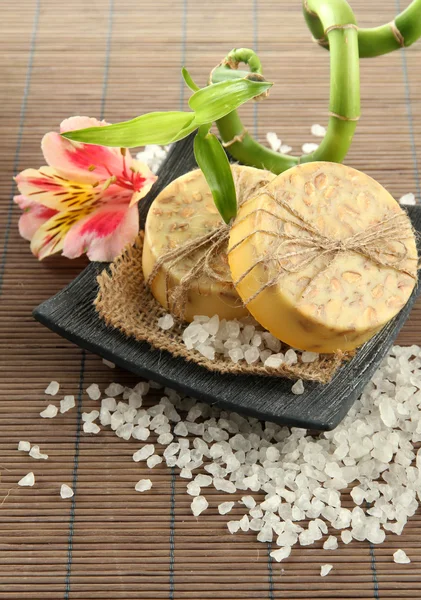 Sabão feito à mão e sal marinho em esteira de bambu cinza — Fotografia de Stock