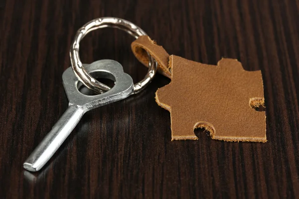 Llave con baratija de cuero sobre fondo de madera — Foto de Stock