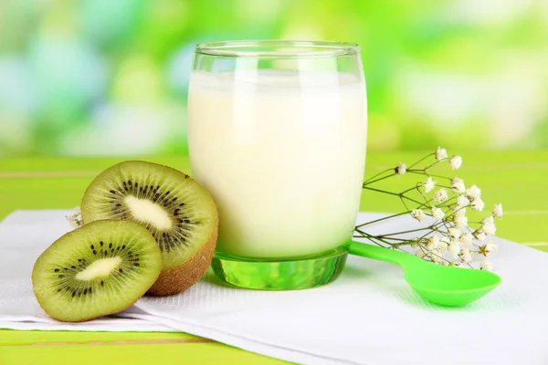 Iogurte delicioso com kiwi em vidro na mesa de madeira no fundo natural — Fotografia de Stock