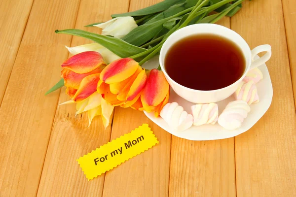 Samenstelling van tulpen en cup met sommige drankje, op houten achtergrond — Stockfoto