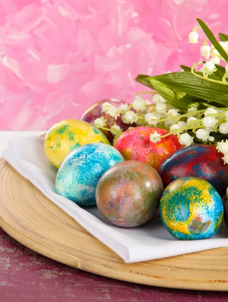 Huevos de Pascua en plato de madera en servilleta con flores de cerca —  Fotos de Stock