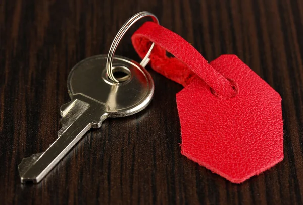 Key with leather trinket on wooden background — Stock Photo, Image