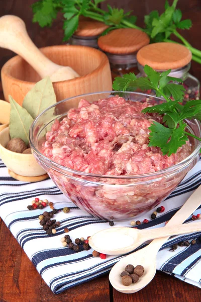 Bowl of raw ground meat with spices on wooden table Royalty Free Stock Images