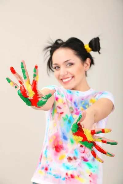 Junge hübsche Malerin mit Händen in Farbe, auf grauem Hintergrund — Stockfoto