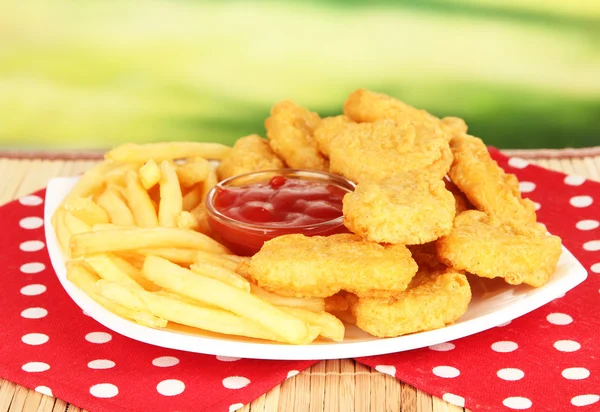 Fried chicken nuggets with french fries and sauce on table in park — Stock Photo, Image