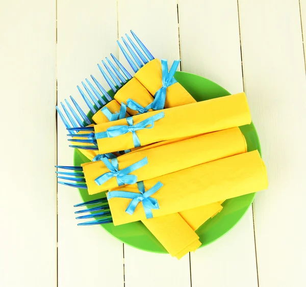 Blauwe plastic vorken verpakt in gele papieren servetten, op een houten achtergrond kleur — Stockfoto