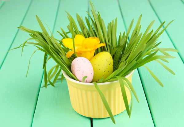 Easter egg in bowl with grass on green wooden table close up — Stock Photo, Image