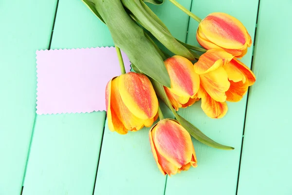 Schöne orange Tulpen auf farbigem Holzhintergrund — Stockfoto