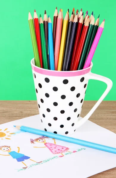 Crayons colorés en tasse sur table sur fond vert — Photo