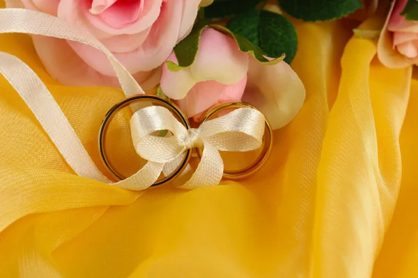 Anillos de boda atados con cinta sobre fondo brillante — Foto de Stock