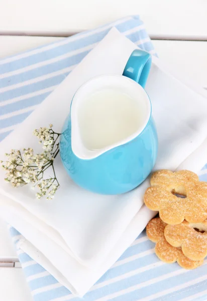 Blue jug with milk and cookies on wooden picnic table close-up — Stock Photo, Image