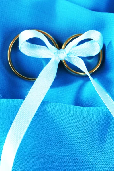 Wedding rings tied with ribbon on cloth background — Stock Photo, Image