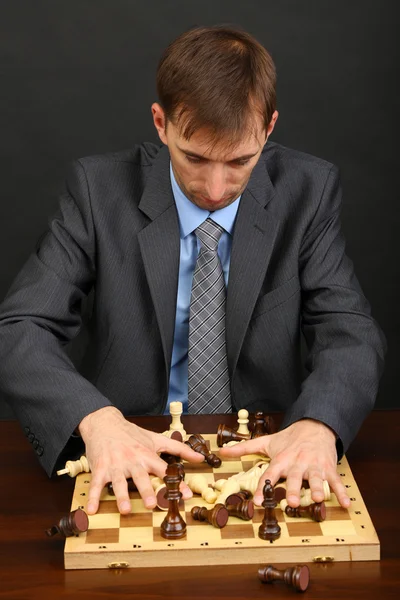 Junger Geschäftsmann spielt Schach auf schwarzem Hintergrund — Stockfoto