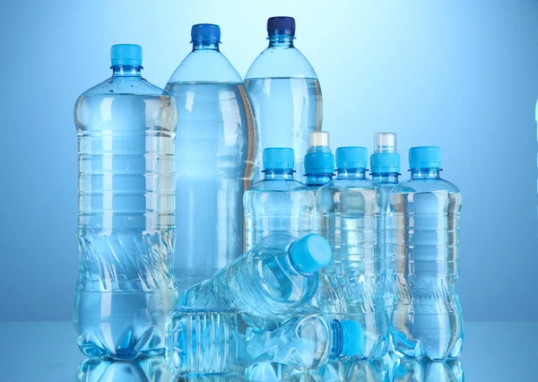 Verschillende flessen water op blauwe achtergrond — Stockfoto