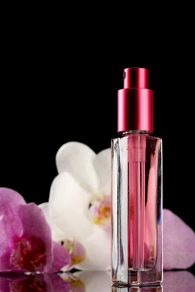 Parfum de femme en belle bouteille et fleurs d'orchidée, sur fond noir — Photo