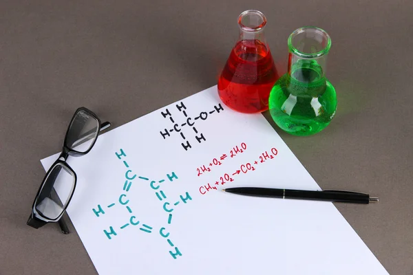 Тестовые трубки с красочными жидкостями и формулами на сером фоне — стоковое фото