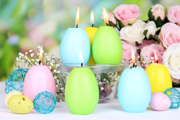 Easter candles with flowers on bright background — Stock Photo, Image