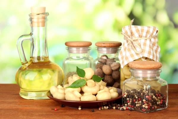 Composición de deliciosos champiñones marinados, aceite y especias sobre mesa de madera sobre fondo brillante —  Fotos de Stock