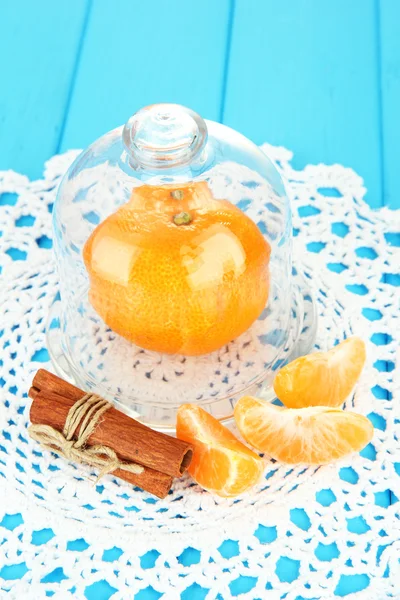 Tangerine on saucer under glass cover on blue background — Stok Foto