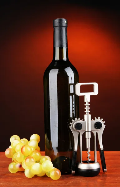 Komposition aus Korkenzieher und Flasche Wein, Traube, auf Holztisch auf dunklem Hintergrund — Stockfoto