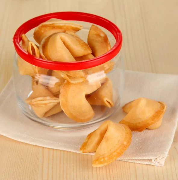 Fortune cookies in glass jar, on wooden table — Stock Photo, Image