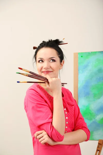 Hermosa joven pintora en el trabajo, sobre fondo de color — Foto de Stock