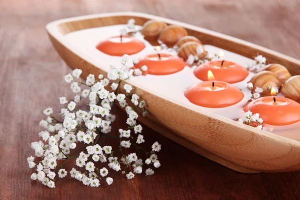 Красивые свечи в воде на деревянном столе крупным планом — стоковое фото