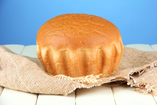 Pão saboroso quente, em pano de saco no fundo de cor — Fotografia de Stock