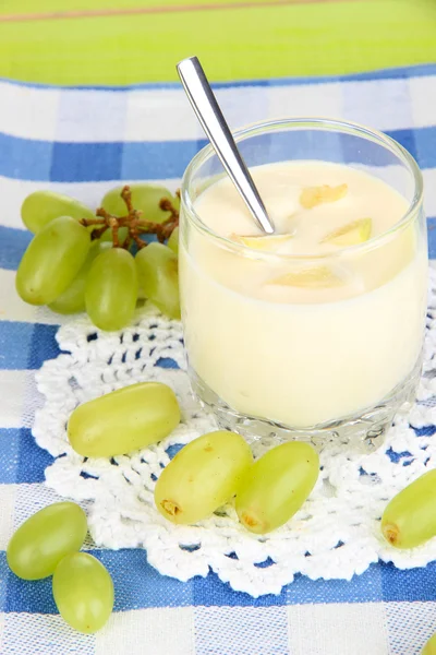 Köstlicher Joghurt im Glas mit Trauben auf blauer Tischdecke — Stockfoto