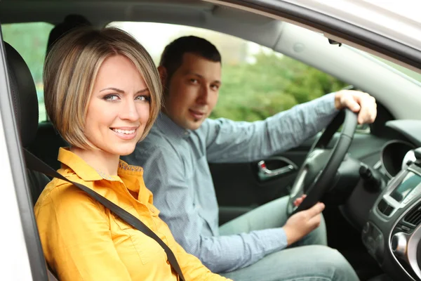 Retrato de una hermosa pareja joven sentada en el coche — Foto de Stock