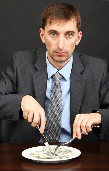 Young businessman having dinner dollars on black background — Stock Photo, Image