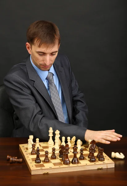 Joven hombre de negocios jugando ajedrez sobre fondo negro — Foto de Stock