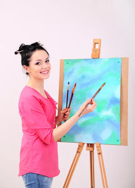 Beautiful young woman painter at work, on color background — Stock Photo, Image