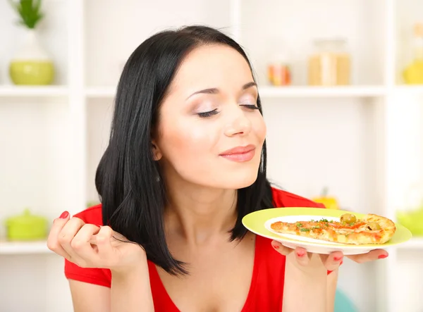 Fille avec délicieuse pizza sur fond de cuisine — Photo