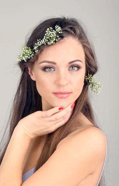 Jovem com belo penteado e grinalda em fundo cinza — Fotografia de Stock