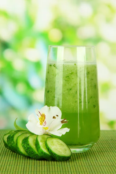 Glass of cucumber juice, on bamboo mat, on green background — Stock Photo, Image