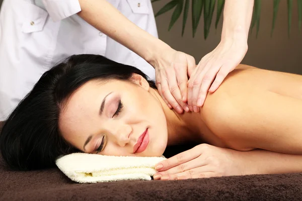 Beautiful young woman in spa salon getting massage, on dark background — Stock Photo, Image