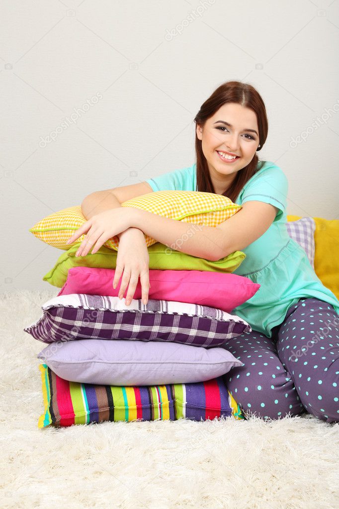 Beautiful young girl with pillows in room