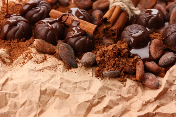 Composition of chocolate sweets, cocoa and spices on brown background — Stock Photo, Image