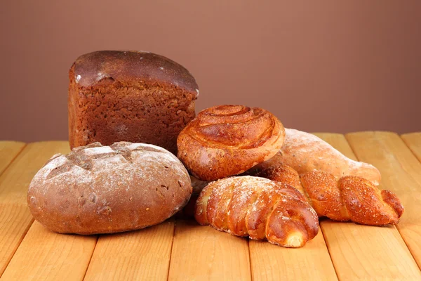 Samenstelling met brood en broodjes op houten tafel, op een achtergrond met kleur — Stockfoto