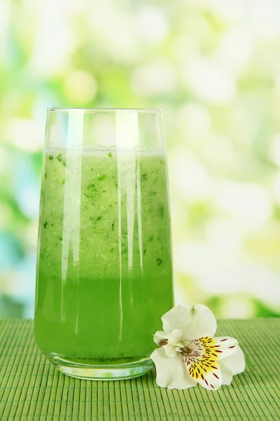 Bicchiere di succo di cetriolo, su tappetino di bambù, su sfondo verde — Foto Stock