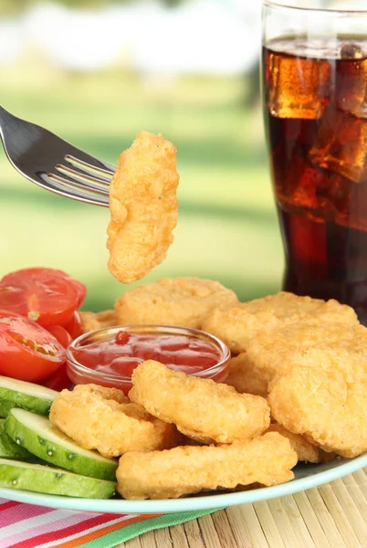 Fried chicken nuggets with vegetables,cola and sauce on table in park — Stock Photo, Image