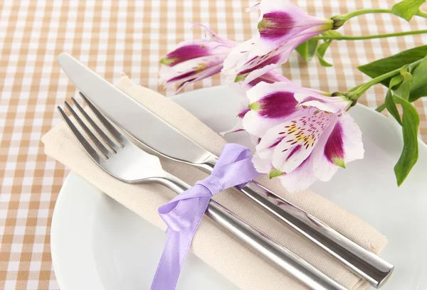 Mesa de comedor festiva con flores sobre fondo a cuadros —  Fotos de Stock