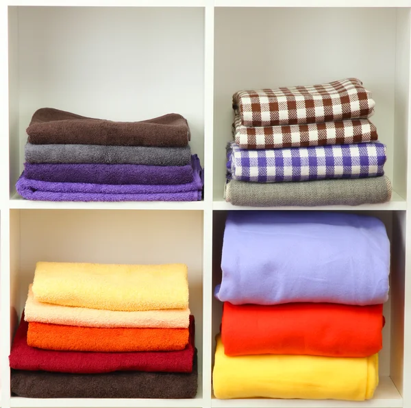 Ljusa handdukar och filtar på hyllor, isolerad på vit — Stockfoto