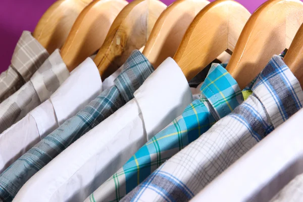 Men's shirts on hangers on purple background — Stock Photo, Image