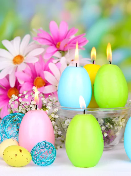 Osterkerzen mit Blumen auf hellem Hintergrund — Stockfoto