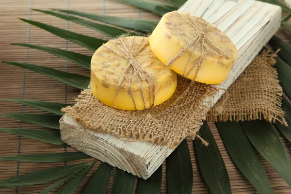 Handgemachte Seife und Palmblatt auf grauer Bambusmatte — Stockfoto