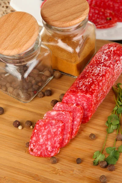Tasty salami on plate and board on wooden table close-up — Stock Photo, Image