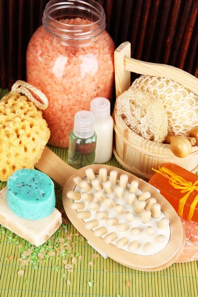 Limpador, escova e cosméticos para chuveiro na mesa sobre fundo de bambu — Fotografia de Stock