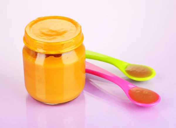 Baby food with weaning spoons on purple background — Stock Photo, Image